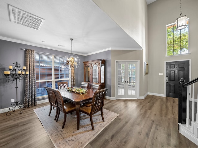 dining room with an inviting chandelier, ornamental molding, hardwood / wood-style flooring, and a healthy amount of sunlight