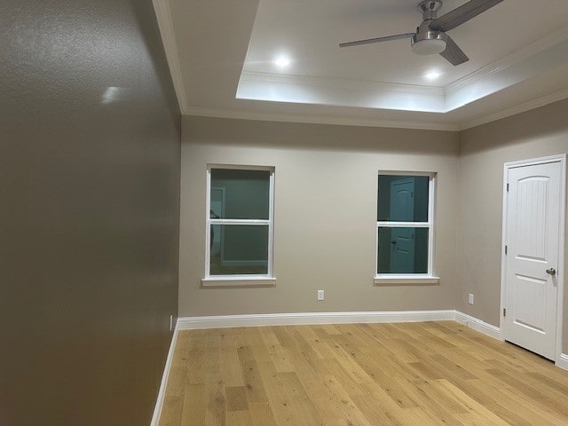 unfurnished room with ceiling fan, ornamental molding, a raised ceiling, and light hardwood / wood-style floors