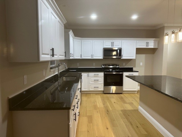 kitchen with light hardwood / wood-style flooring, stainless steel appliances, white cabinets, and crown molding