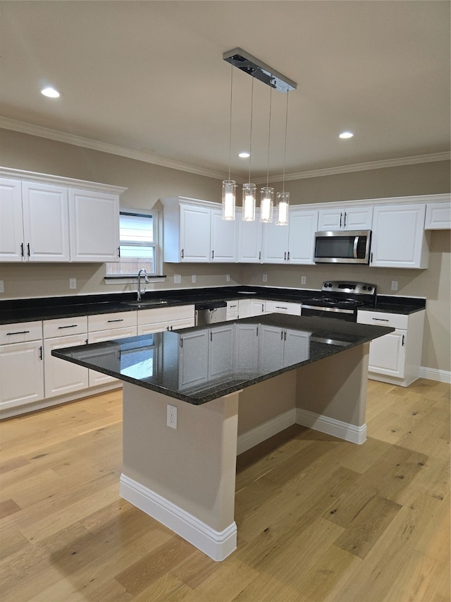 kitchen with stainless steel appliances, white cabinetry, light hardwood / wood-style floors, and a kitchen island