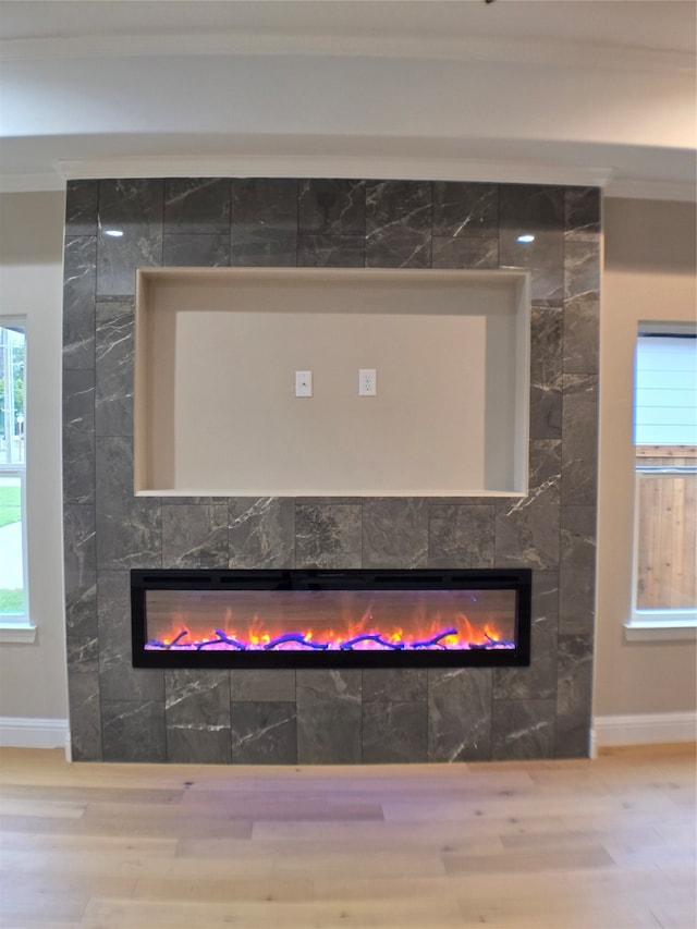 details featuring ornamental molding, a tile fireplace, and hardwood / wood-style floors