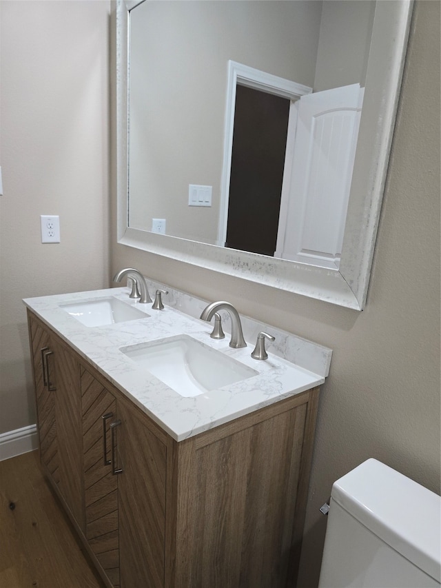 bathroom with wood-type flooring, vanity, and toilet