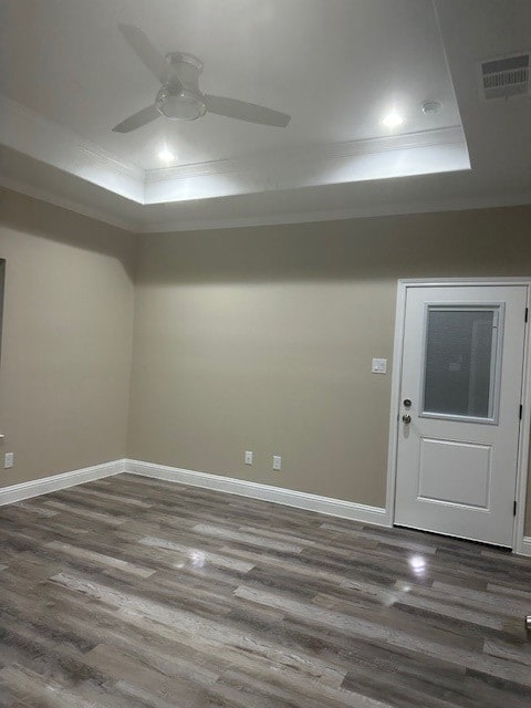 spare room with ceiling fan, a raised ceiling, and dark wood-type flooring