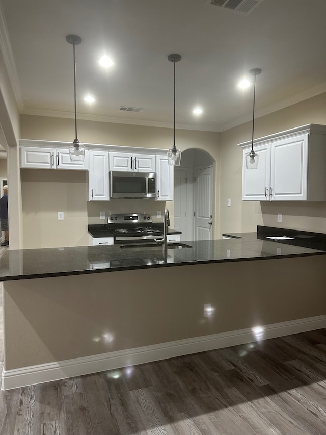 kitchen with hanging light fixtures, stainless steel appliances, and white cabinets