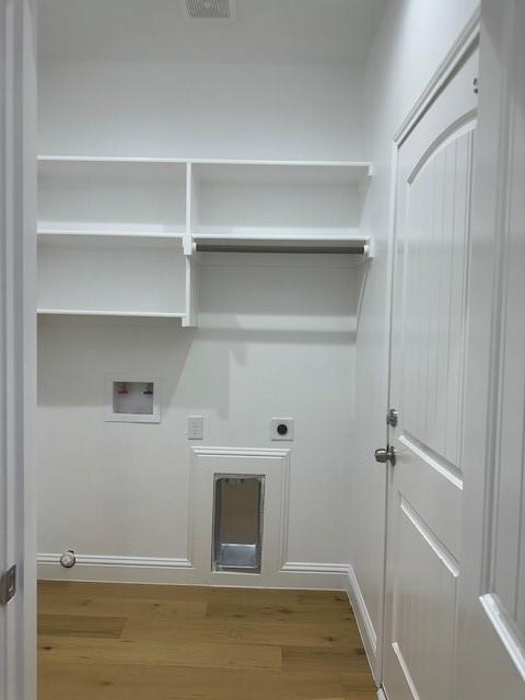 1010 S Preston St, Ennis, TX 75119 - laundry room with wood finished floors, hookup for an electric dryer, hookup for a washing machine, baseboards, and gas dryer hookup