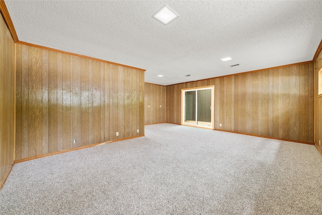 spare room with light colored carpet, wooden walls, and a textured ceiling