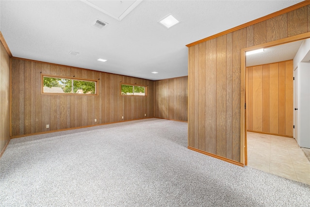 carpeted empty room featuring wood walls