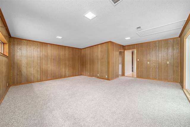 spare room featuring a textured ceiling, wooden walls, and light carpet