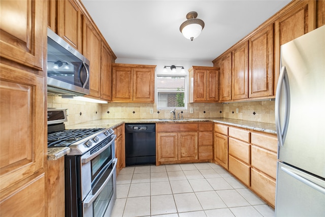 kitchen featuring sink, light tile patterned floors, tasteful backsplash, stainless steel appliances, and light stone countertops