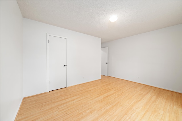 unfurnished room with light wood-type flooring and a textured ceiling