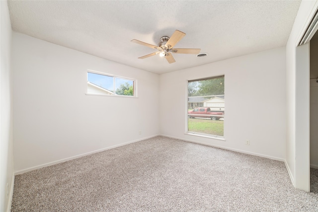 empty room with ceiling fan, carpet flooring, and a textured ceiling