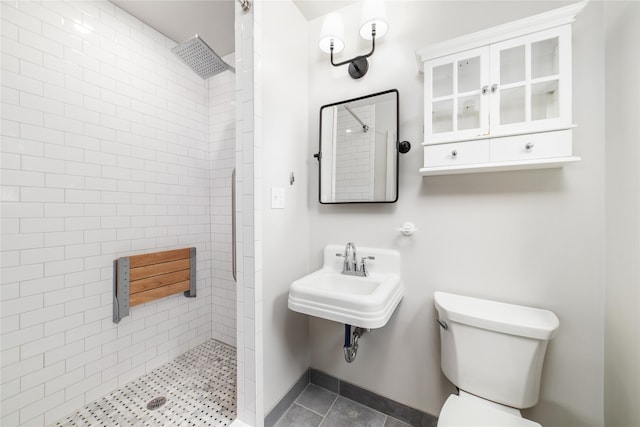 bathroom with tile patterned floors, sink, tiled shower, and toilet