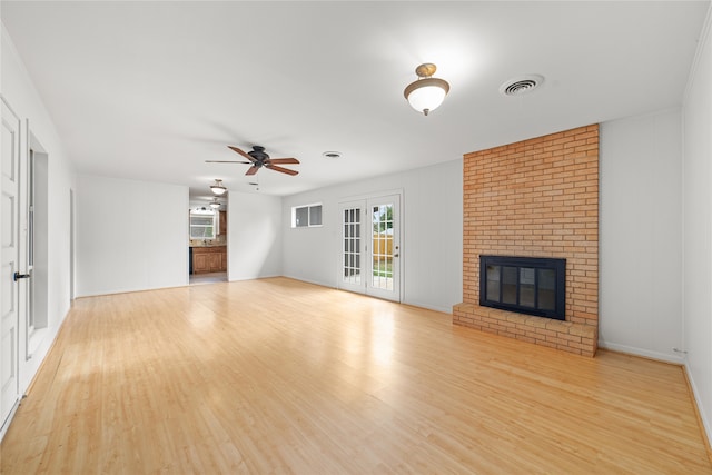 unfurnished living room featuring a brick fireplace, ceiling fan, light hardwood / wood-style floors, and a wealth of natural light