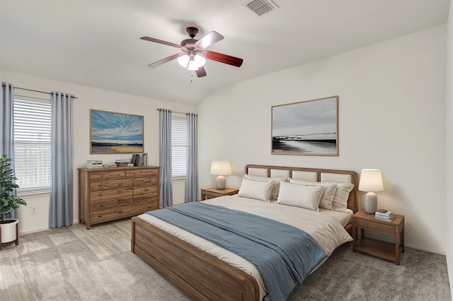 bedroom with light hardwood / wood-style flooring, vaulted ceiling, and ceiling fan