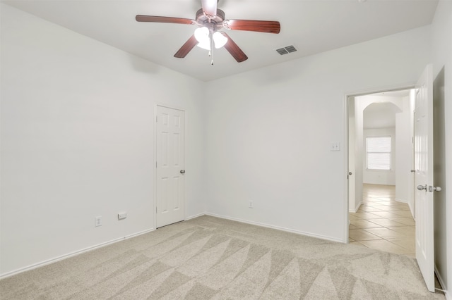 empty room featuring ceiling fan and light colored carpet