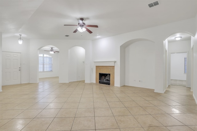 unfurnished living room with ceiling fan, light tile patterned floors, and a tile fireplace