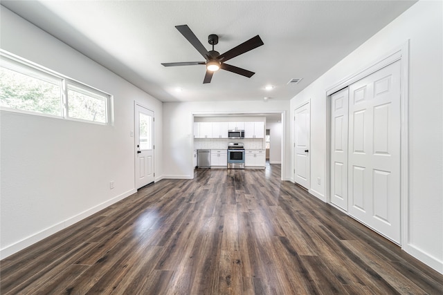 unfurnished living room featuring ceiling fan and dark wood-type flooring