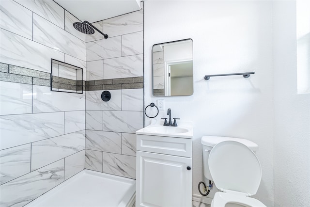 bathroom featuring a tile shower, vanity, and toilet