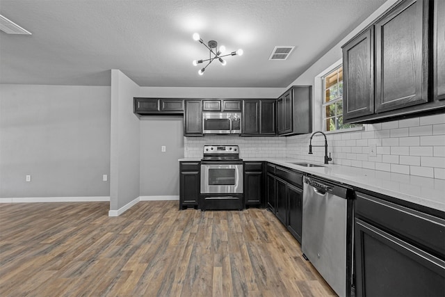 kitchen featuring appliances with stainless steel finishes, dark hardwood / wood-style flooring, a textured ceiling, sink, and a chandelier