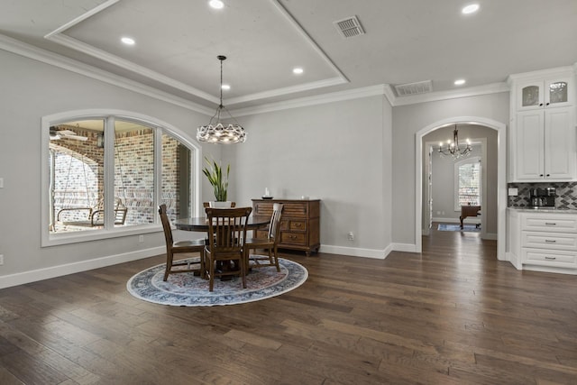dining area featuring dark wood finished floors, arched walkways, a tray ceiling, and visible vents
