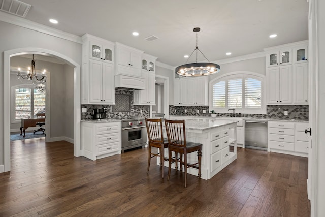 kitchen featuring appliances with stainless steel finishes, white cabinetry, dark wood-type flooring, a kitchen island, and decorative light fixtures