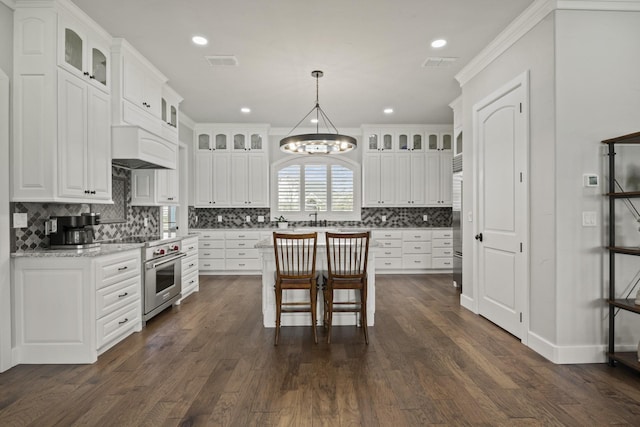 kitchen with high end stainless steel range oven, decorative backsplash, dark wood-style floors, visible vents, and white cabinets