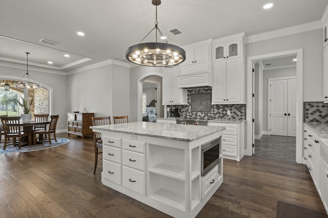 kitchen with arched walkways, visible vents, stainless steel microwave, and an inviting chandelier