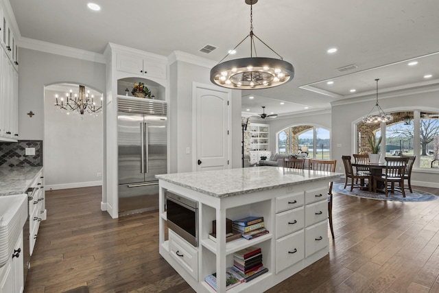 kitchen with dark wood-style floors, built in appliances, ornamental molding, and open shelves