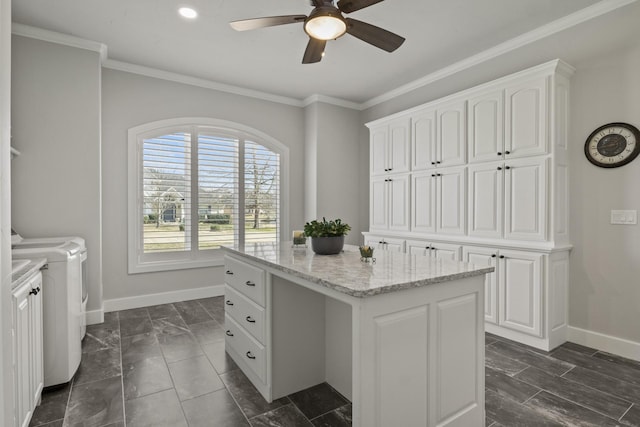 clothes washing area with ornamental molding, a ceiling fan, washer and clothes dryer, and cabinet space