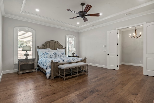 bedroom featuring ceiling fan with notable chandelier, ornamental molding, a tray ceiling, and dark wood-type flooring