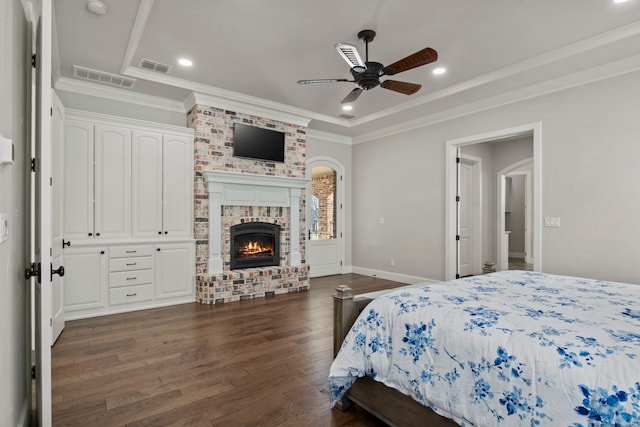 bedroom with ornamental molding, ceiling fan, dark hardwood / wood-style floors, and a fireplace