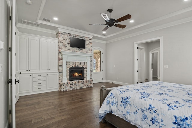 bedroom featuring ornamental molding, visible vents, a brick fireplace, and dark wood finished floors