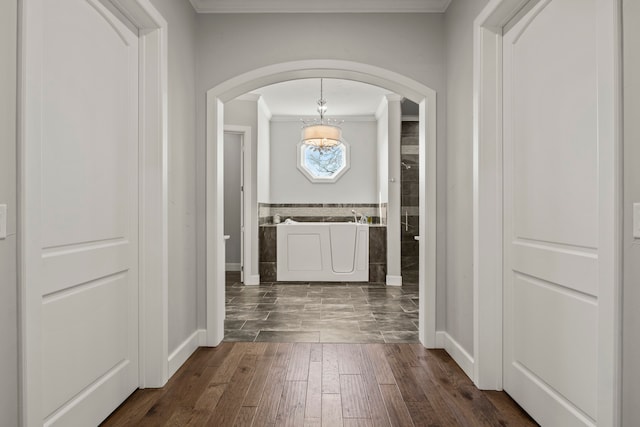 hallway featuring an inviting chandelier and crown molding