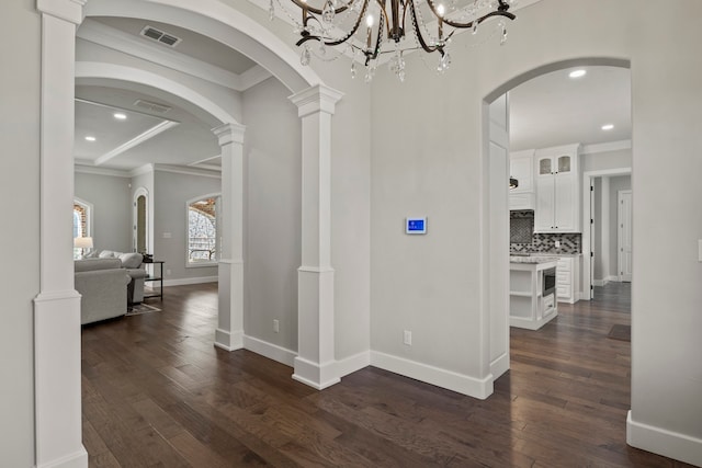 hall featuring a chandelier, decorative columns, crown molding, and dark hardwood / wood-style flooring