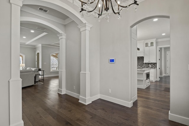 corridor featuring baseboards, visible vents, crown molding, and dark wood finished floors