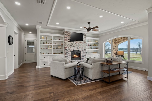 living room featuring ceiling fan, a fireplace, crown molding, and dark wood-type flooring