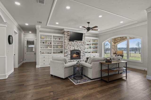 living area featuring a tray ceiling, visible vents, dark wood-style flooring, and a ceiling fan