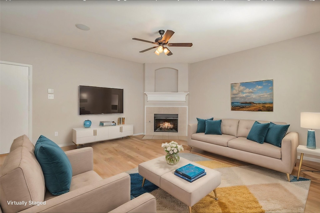 living room with a fireplace, light hardwood / wood-style flooring, and ceiling fan