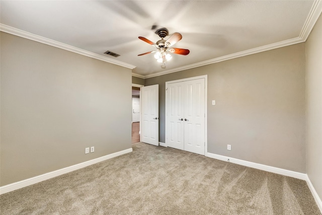 unfurnished bedroom with ornamental molding, a closet, ceiling fan, and carpet flooring