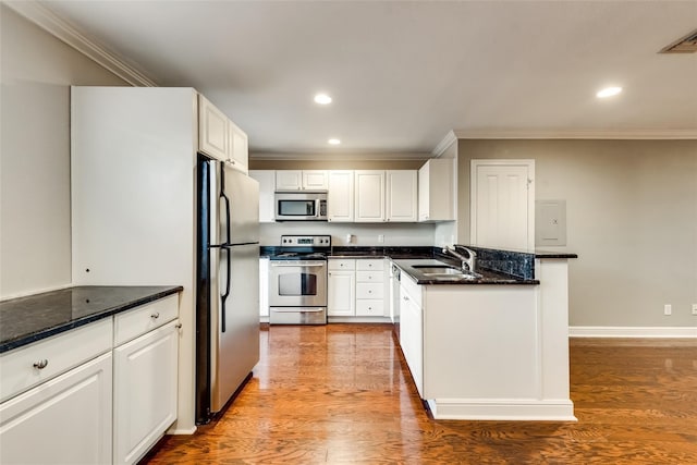 kitchen with white cabinets, sink, hardwood / wood-style flooring, appliances with stainless steel finishes, and crown molding