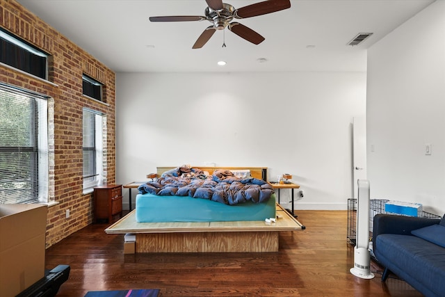 bedroom with dark hardwood / wood-style flooring, ceiling fan, and brick wall