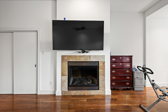 living room featuring a tiled fireplace and dark wood-type flooring