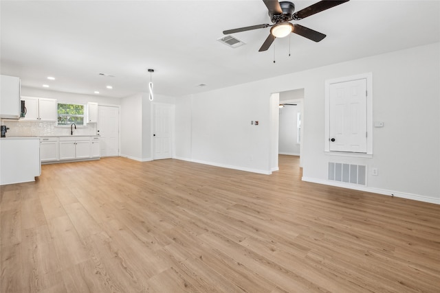 unfurnished living room with ceiling fan, light wood-type flooring, and sink