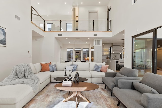 living room with a towering ceiling and light hardwood / wood-style flooring