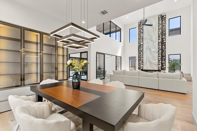 dining space with light hardwood / wood-style flooring and a towering ceiling