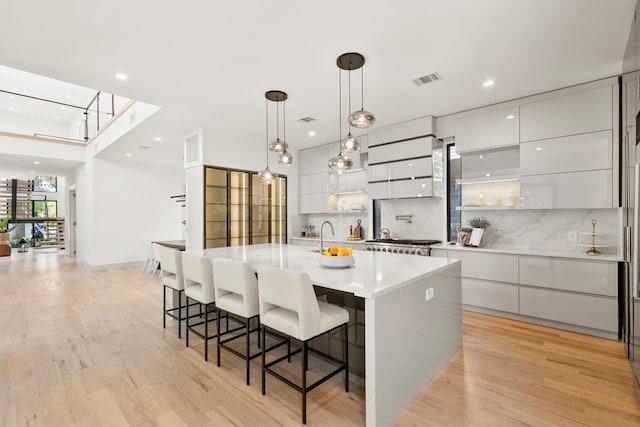 kitchen featuring white cabinets, light hardwood / wood-style floors, decorative light fixtures, and a spacious island