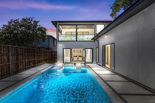 pool at dusk featuring a patio area