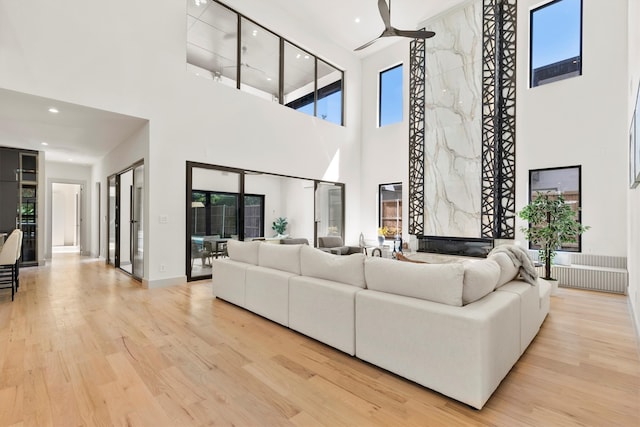 living room featuring light wood-type flooring and a towering ceiling