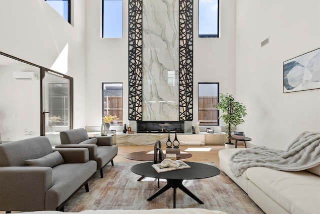 living room featuring a towering ceiling, hardwood / wood-style flooring, plenty of natural light, and a wall mounted AC