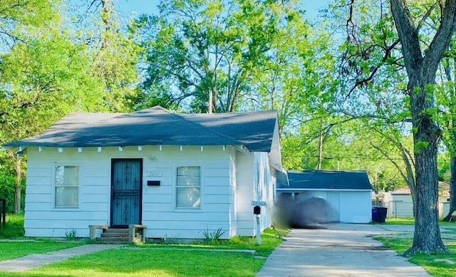 bungalow-style home with a front yard, an outdoor structure, and a garage